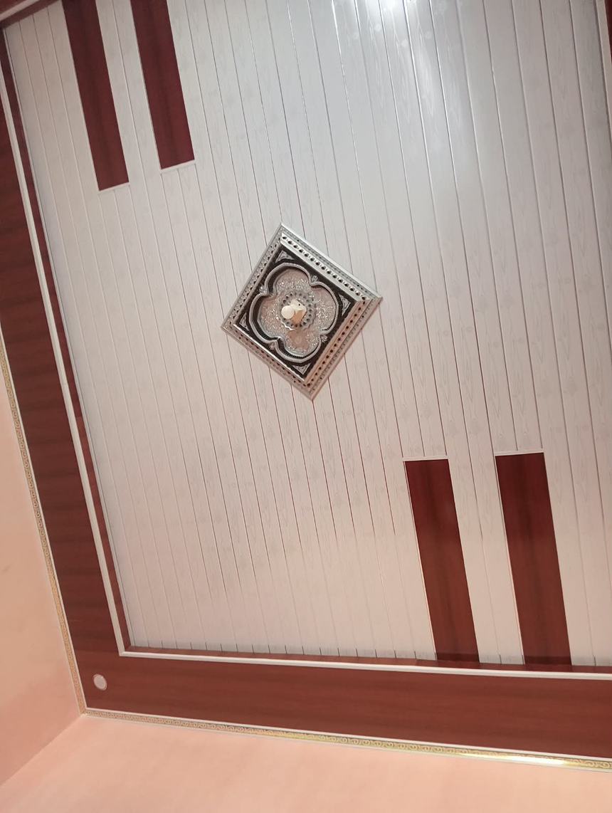 Plafon PVC putih dengan list motif kayu dan ornamen di tengah ruangan